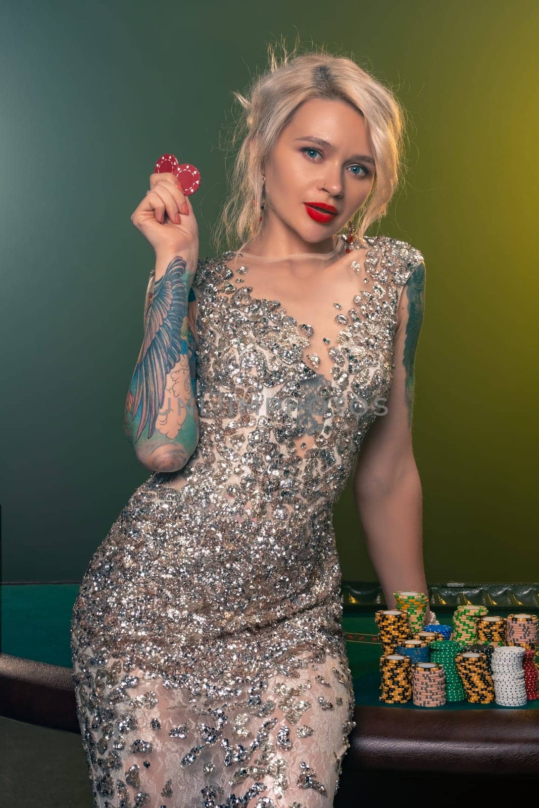 Blonde woman with a beautiful hairstyle and perfect make-up is posing with red gambling chips in her hands. Casino, poker. by nazarovsergey