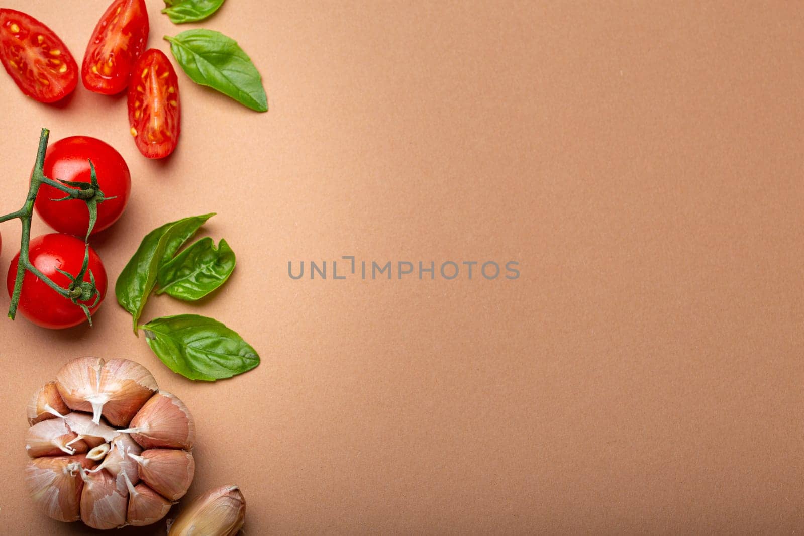 Food cooking border with cherry tomatoes, fresh green basil and garlic cloves top view on simple clean paper background, ingredients for preparing meal, copy space by its_al_dente