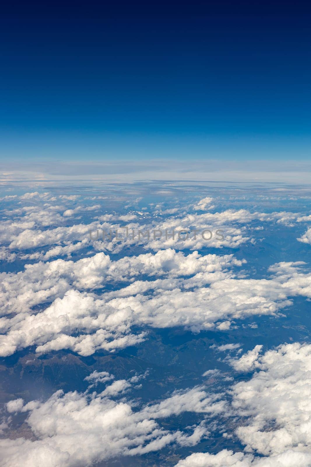 Beautiful view of white clouds above the ground through a porthole window against the background of a blue sky, close-up side view.