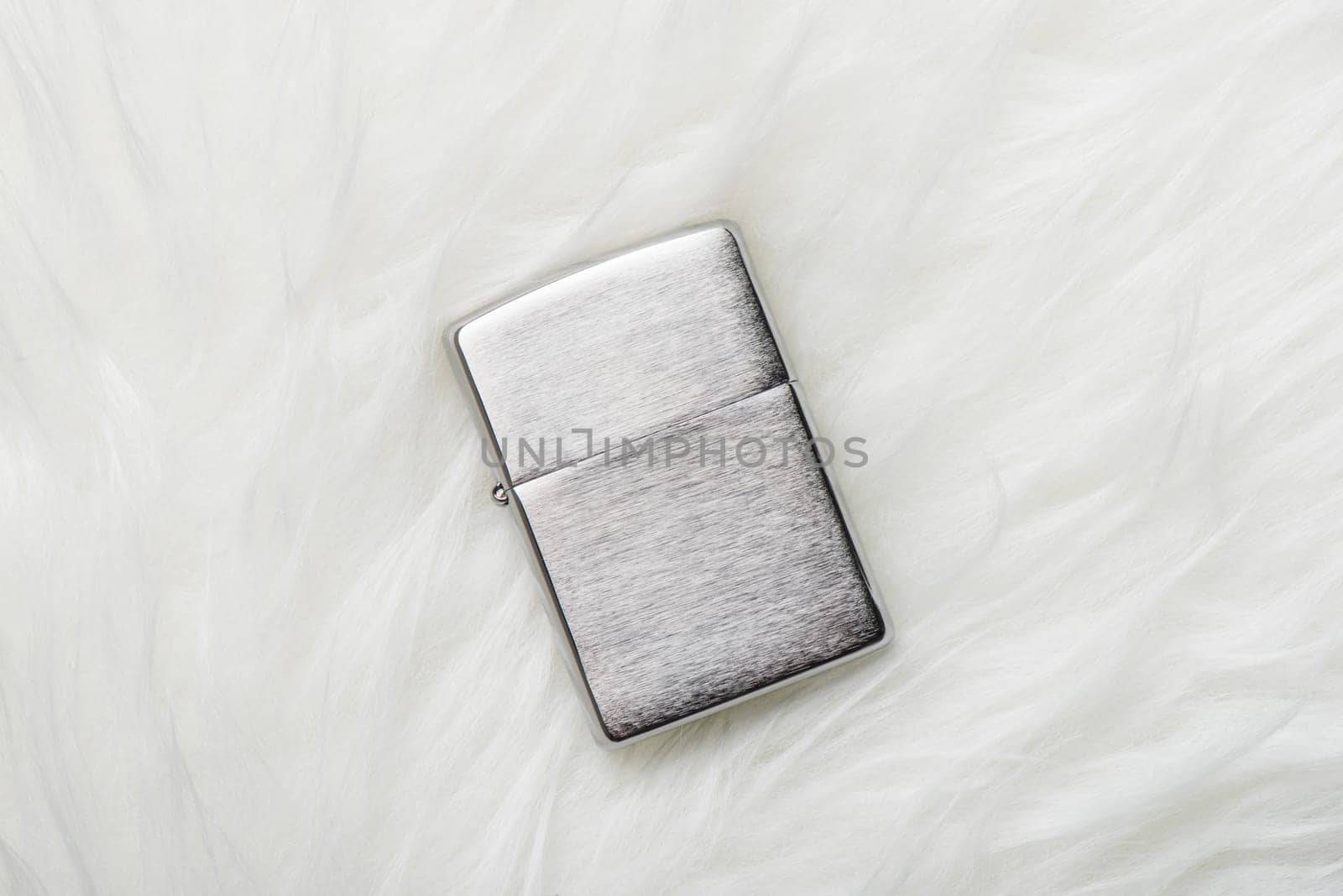 brushed chrome lighter with windproof isolated over white fur.