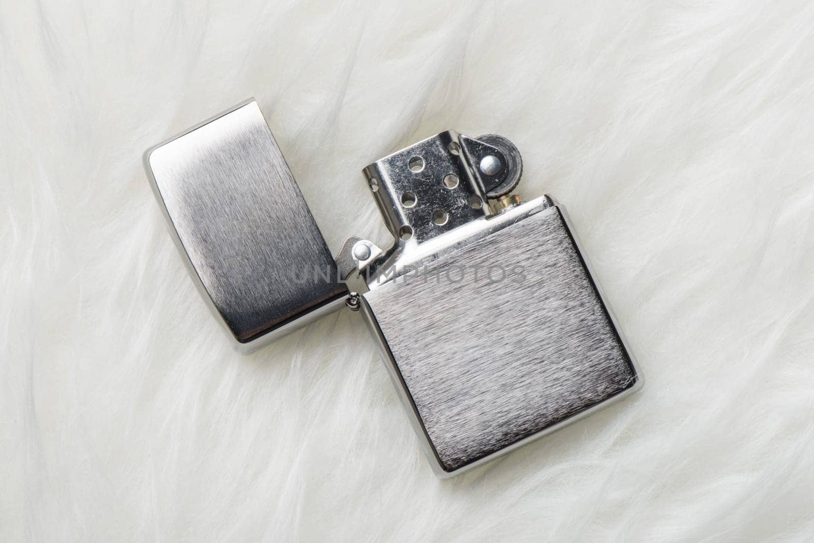 brushed chrome lighter with windproof isolated over white fur.