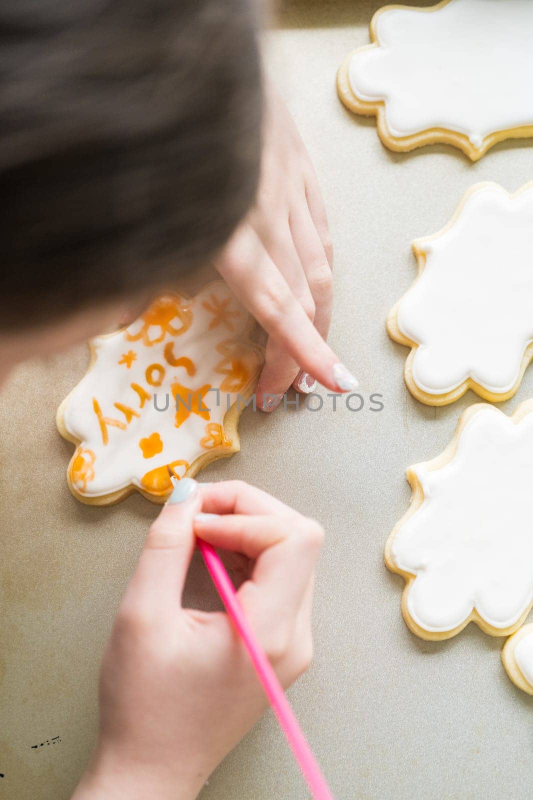 A heartwarming scene of a little girl carefully writing 'Sorry' on sugar cookies with food coloring, the cookies beautifully flooded with white royal icing.