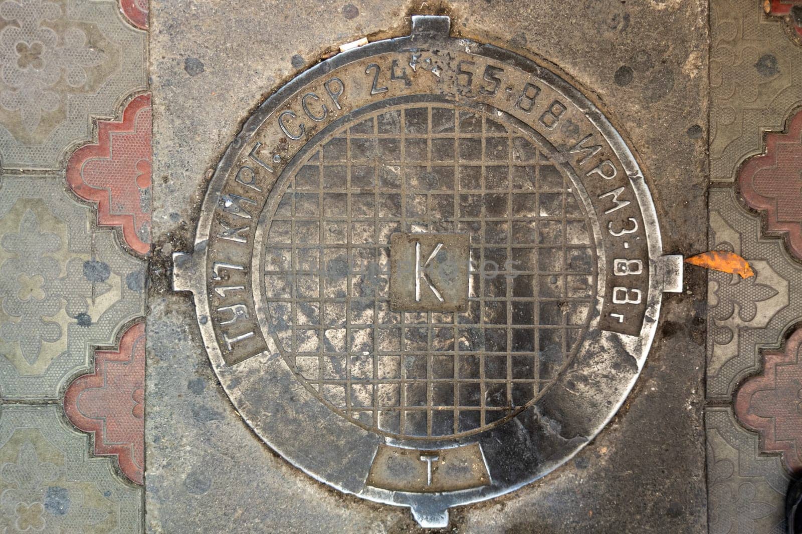 cast iron soviet sewers manhole cover in Kyrgyzstan public market, closeup texture and background by z1b