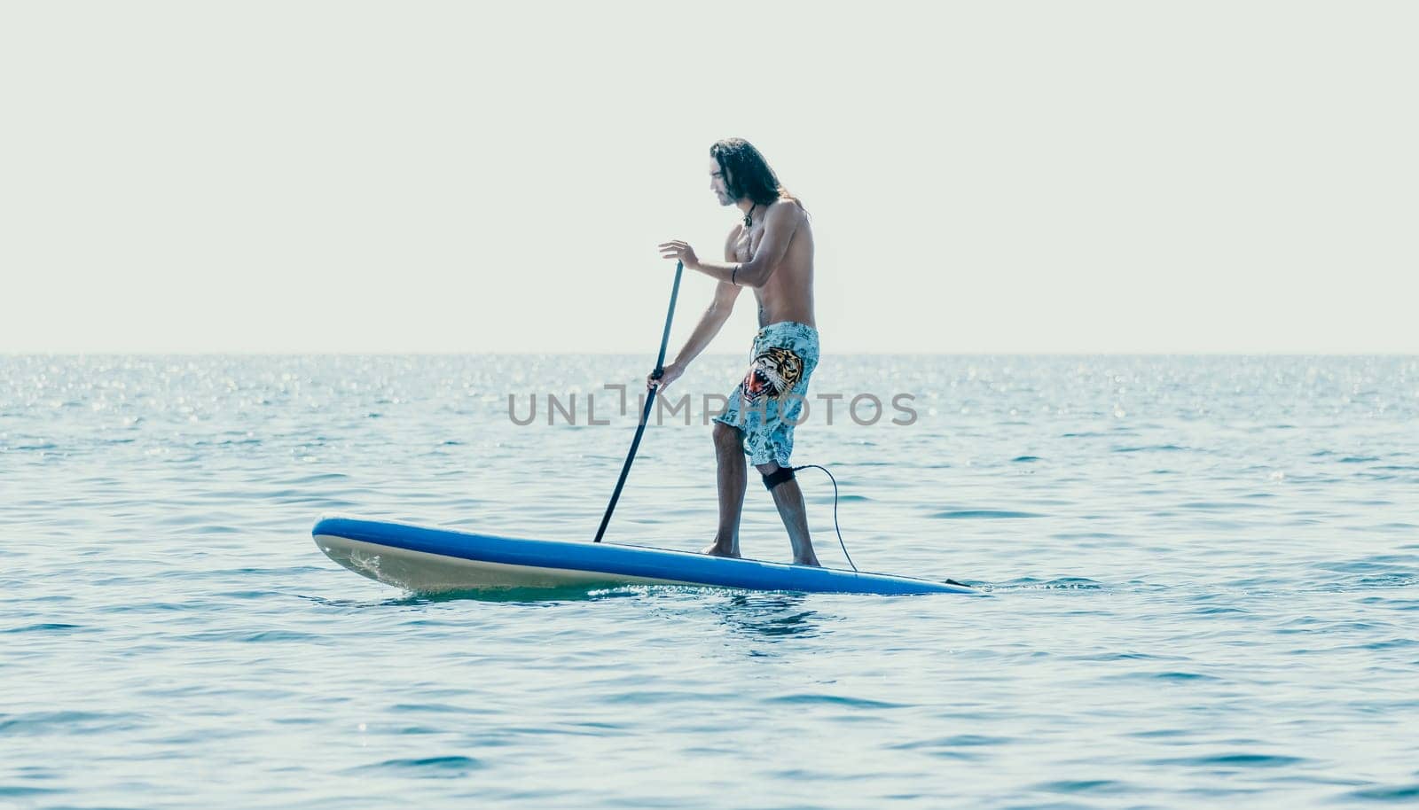 Man Sup Sea. Strong athletic man learns to paddle sup standing on board in open sea ocean on sunny day. Summer holiday vacation and travel concept. Aerial view. Slow motion by panophotograph