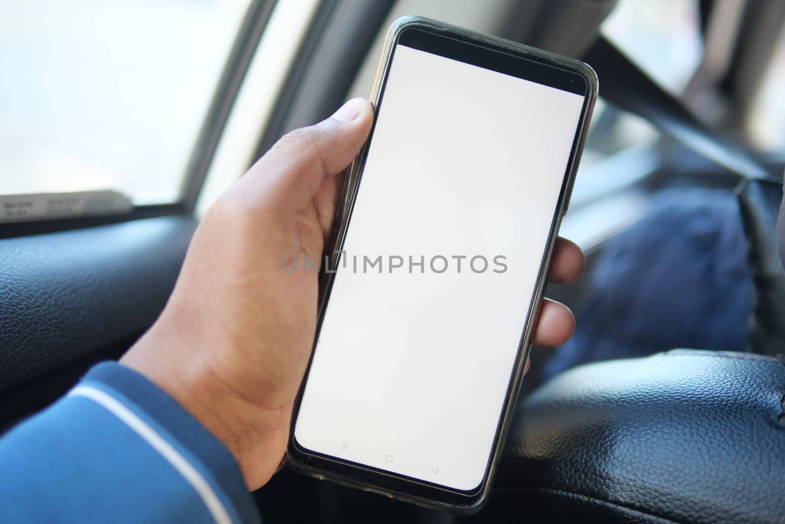 hand holding smart phone with empty screen in a car by towfiq007
