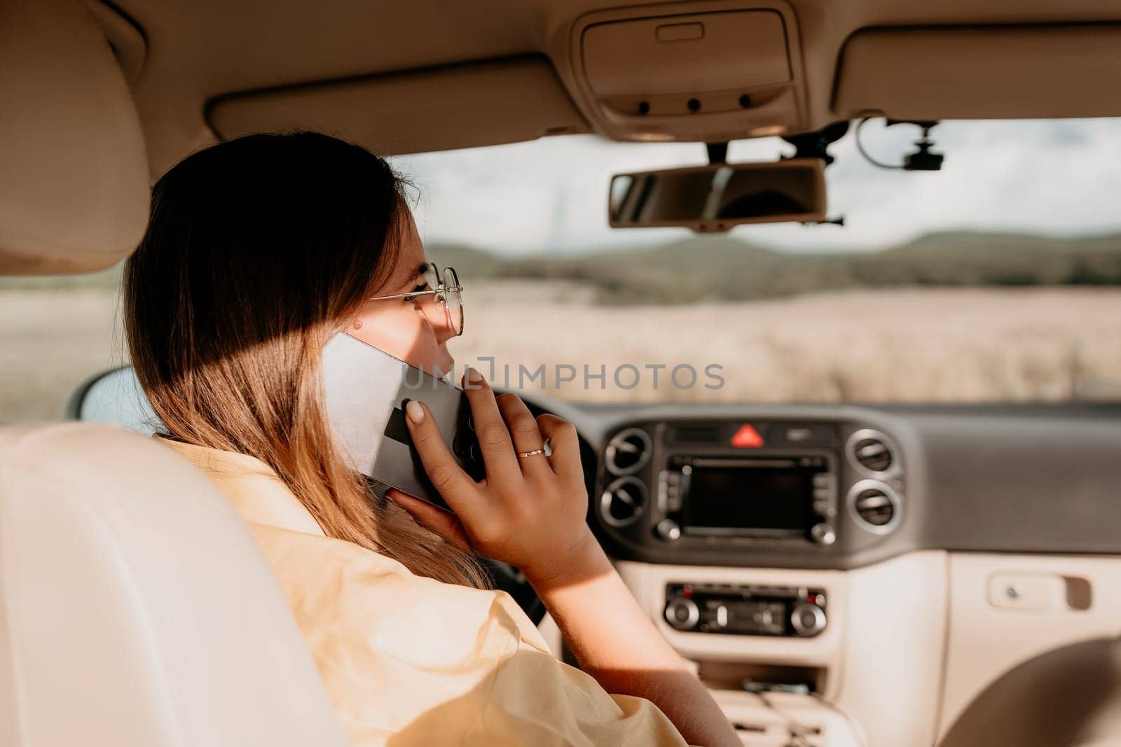 Happy woman talking on the phone while sitting in the car on nature Relaxed video call, professional conversation, female executive in automobile. business woman talking on video call on phone. by panophotograph
