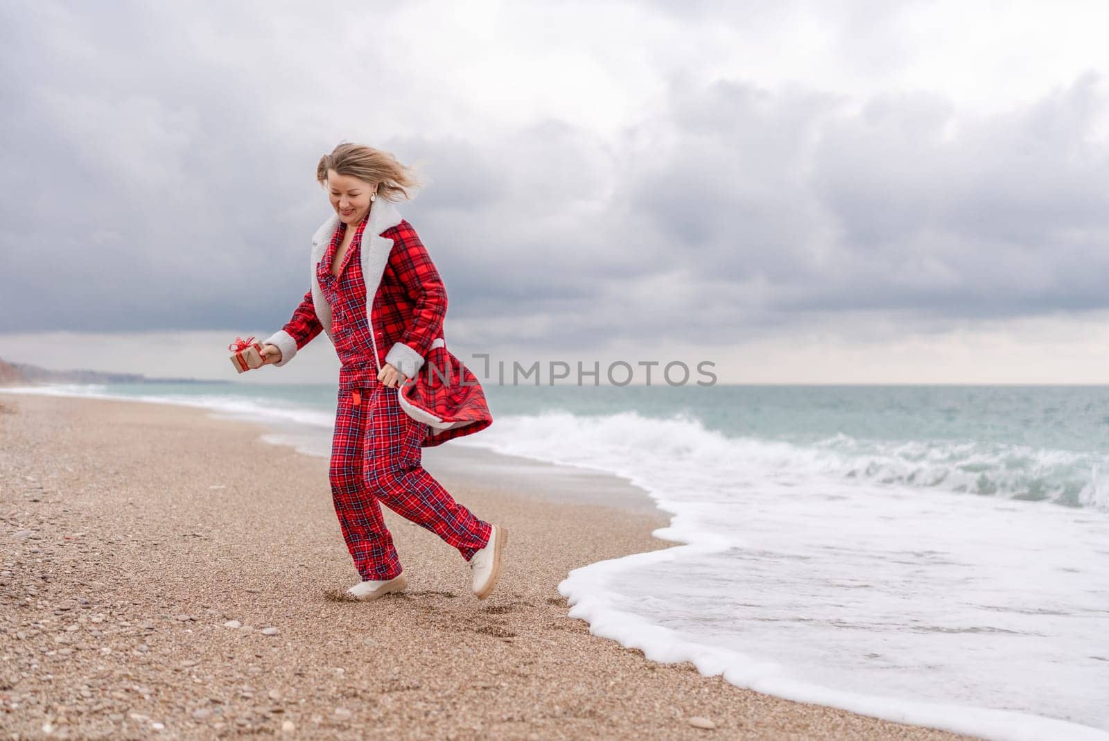 Lady in plaid shirt holding a gift in his hands enjoys beach with Christmas tree. Coastal area. Christmas, New Year holidays concep.