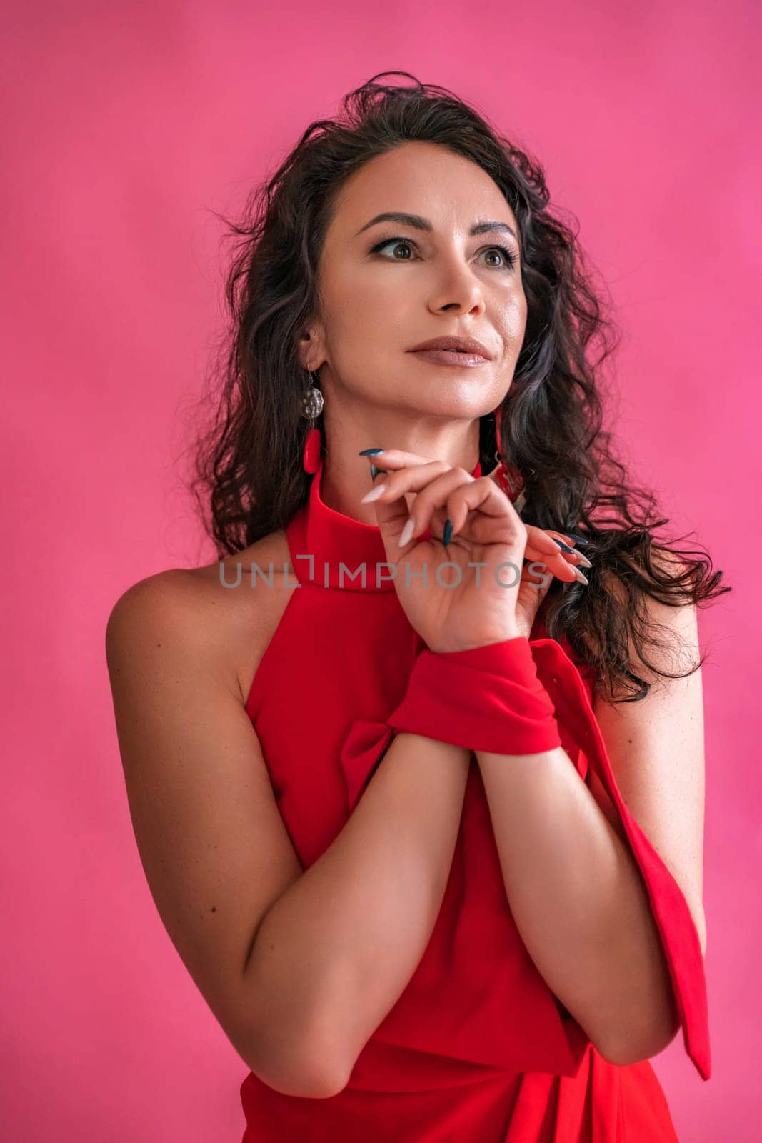 A woman in a red dress is standing in front of a pink background. She is wearing a red scarf and earrings. by Matiunina