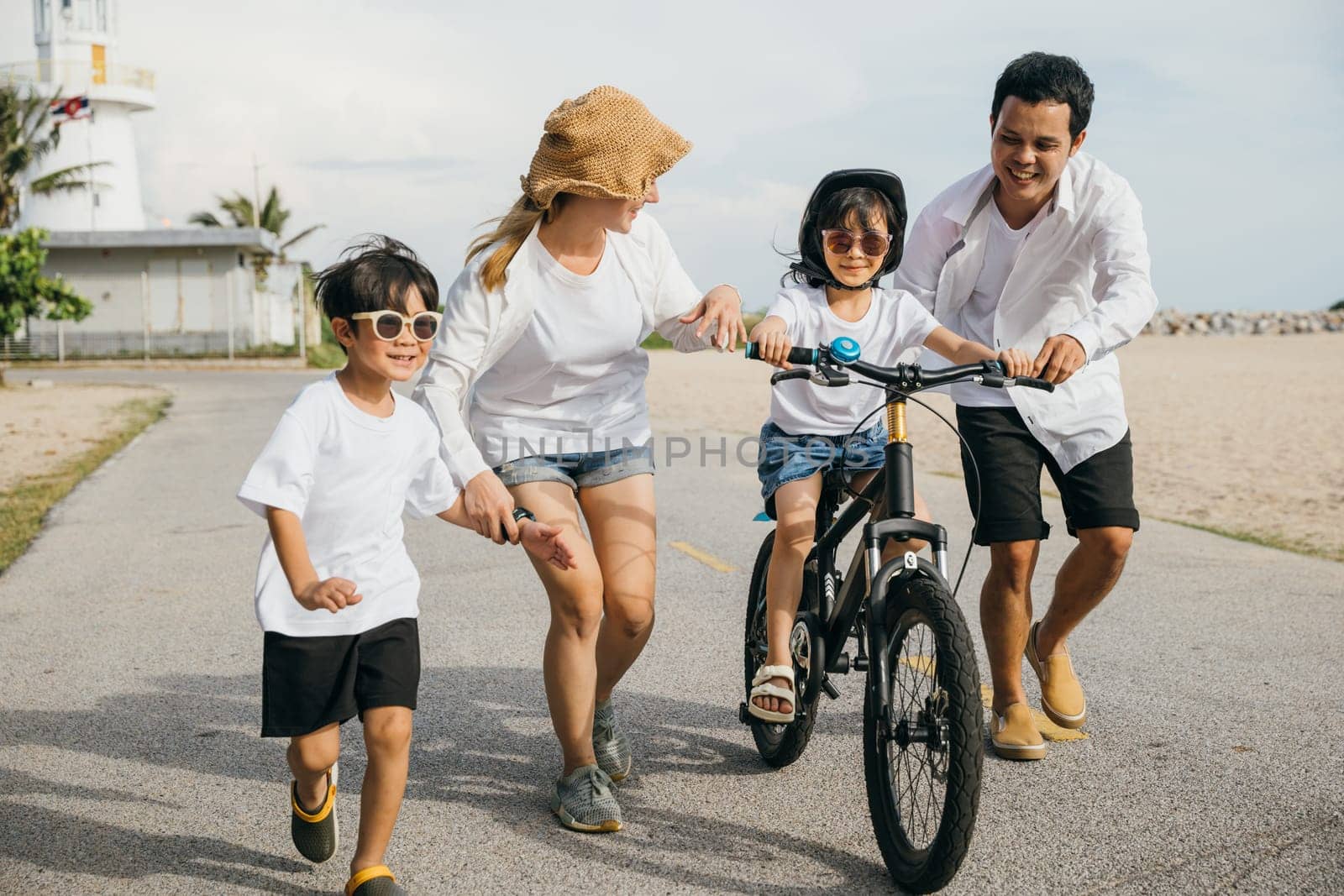 Sunset happiness on a sandy beach, A cheerful family enjoys a road trip teaching and learning bicycle riding. Safety laughter and joy of family bonds make this a perfect tourism day concept. by Sorapop