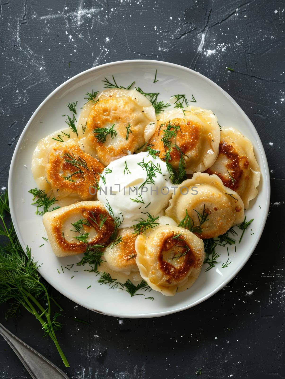 Authentic Polish pierogi, traditional dumplings served on a white plate with a dollop of sour cream and fresh dill - a comforting and delicious representation of Eastern European comfort food. by sfinks