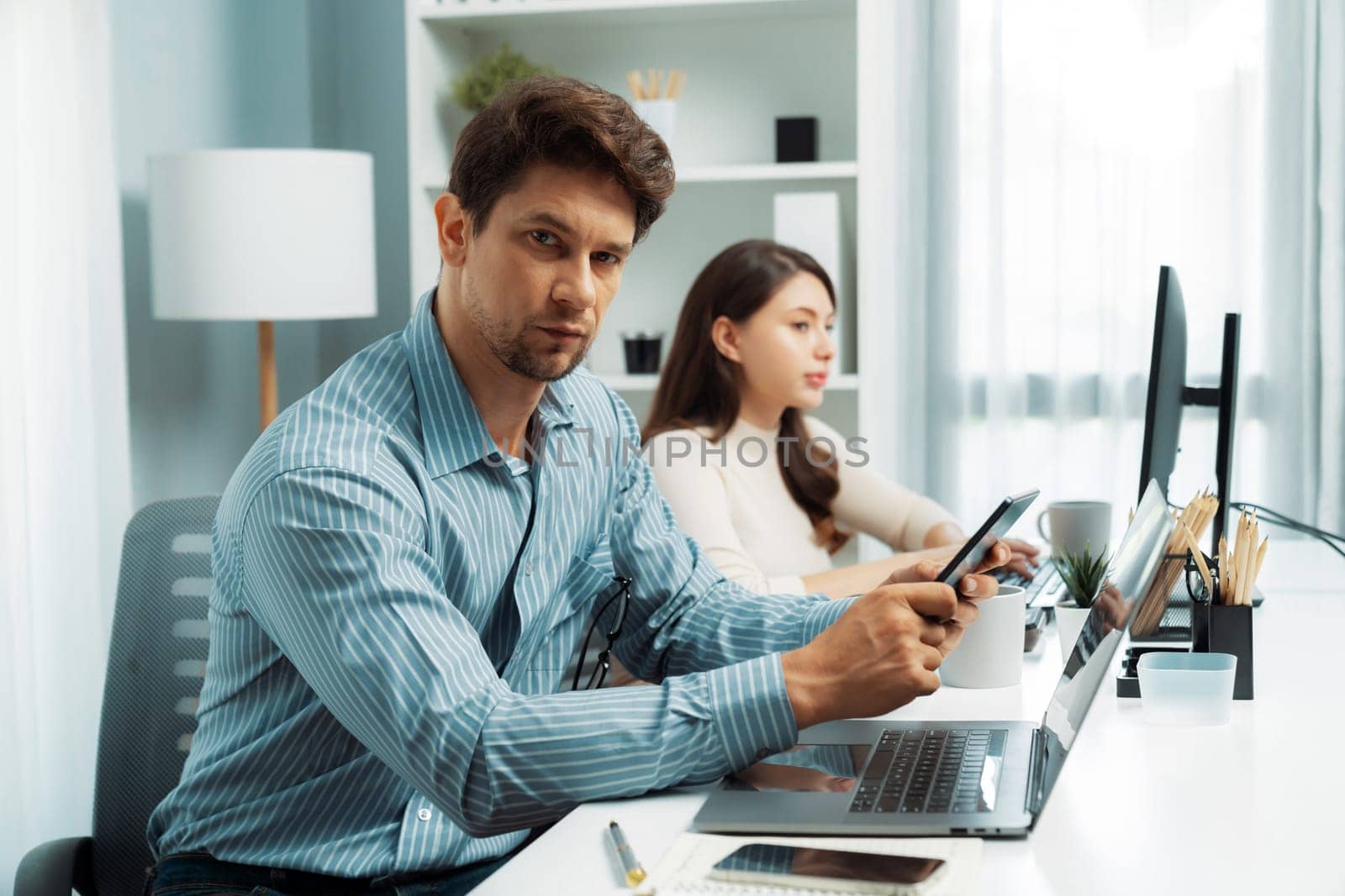 Office worker smart man using tablet and pen to search looking at camera photo shooting portrait business using pen to pose profile with beautiful coworker at modern office at morning time. Postulate.