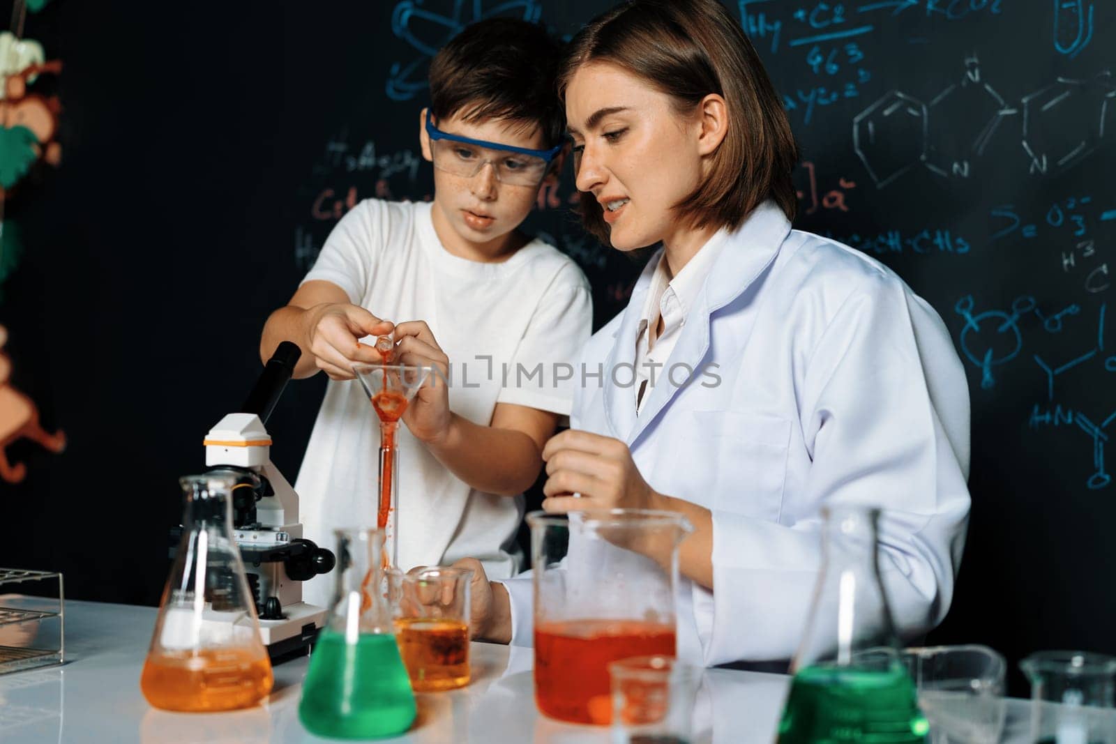Teacher support schoolboy in laboratory. Schoolboy and teacher stand and experiment about science of chemistry in STEM class using liquid in glass container. Instructor mixing solution. Erudition.
