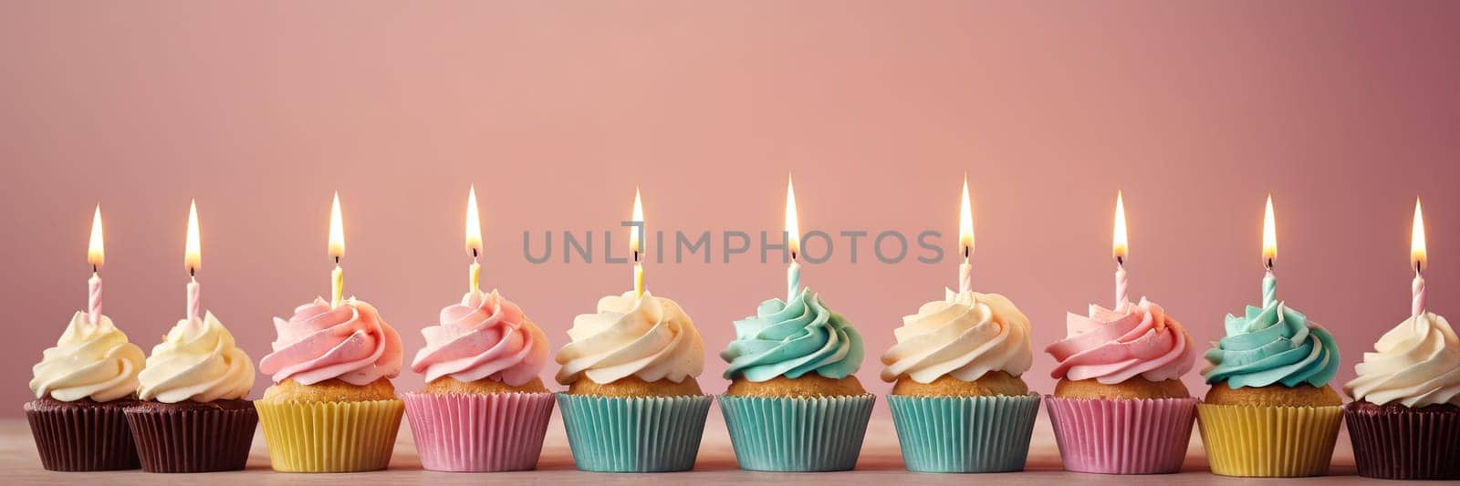 Colorful cupcakes with lit candles are displayed against a pink background, indicating an indoor celebration event marking of joy and celebrating. with free space by Matiunina