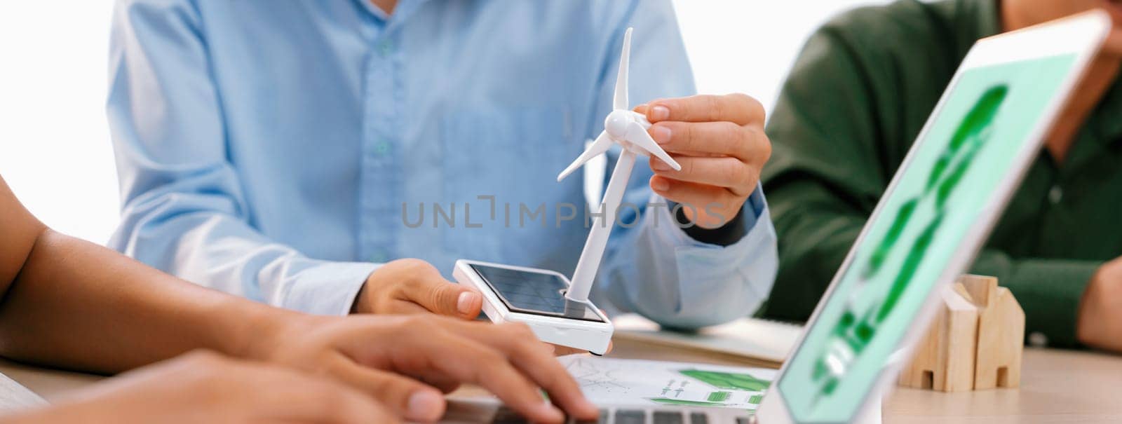Professional businessman sees opportunity in the growing clean energy market at meeting room on table with windmill represented clean energy scatter around. Closeup. Focus on hand. Delineation