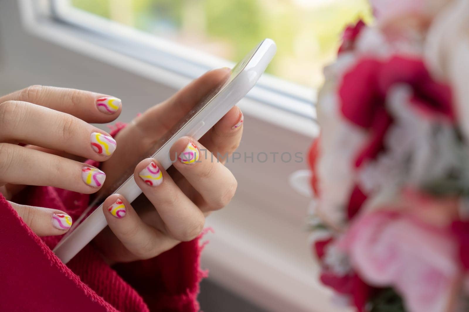 Woman manicured hands holding mobile phone, stylish summer colorful nails. Closeup of manicured nails of female hand. Summer style of nail design concept. Beauty treatment.