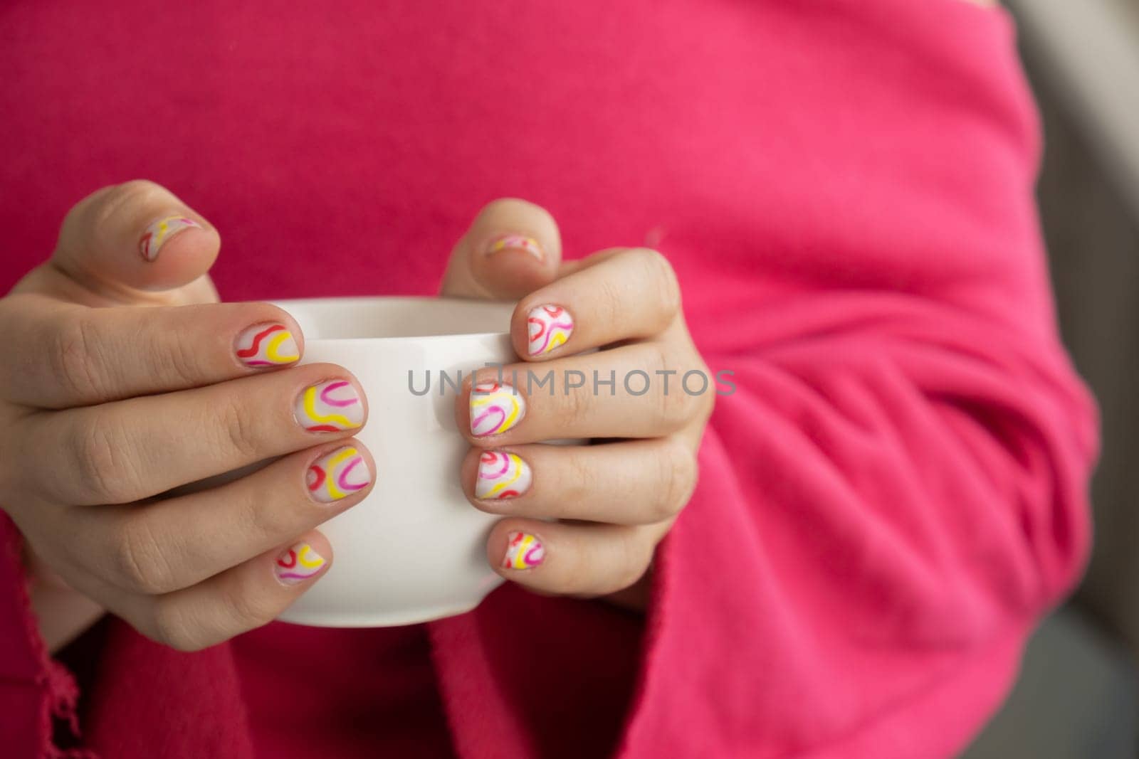 Pastel softness colorful manicured nails. Woman holding white cup of coffee or tea showing her new summer manicure in colors of pastel palette. Simplicity decor fresh spring vibes earth-colored neutral tones by anna_stasiia