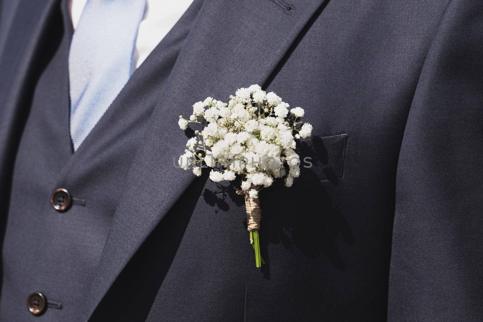 Groom with gypsophila flowers boutonniere at a wedding