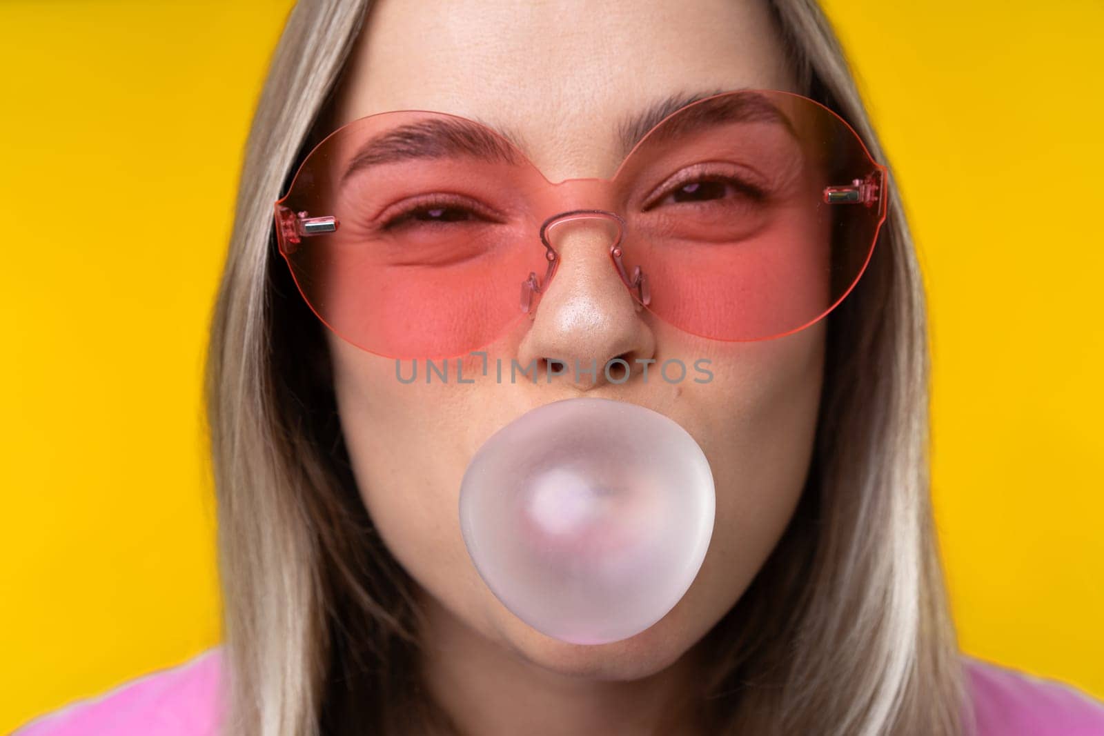 Happy emotions concept. Positive and beautiful young woman laughs poisitively looks aside with carefree face expression wears casual orange sweater isolated over yellow studio background.