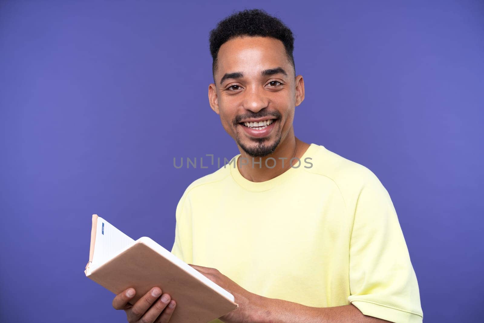 Emotional young black guy in casual raising fists up studio background, celebrating success, happy handsome african american millennial man sharing good emotions, copy space