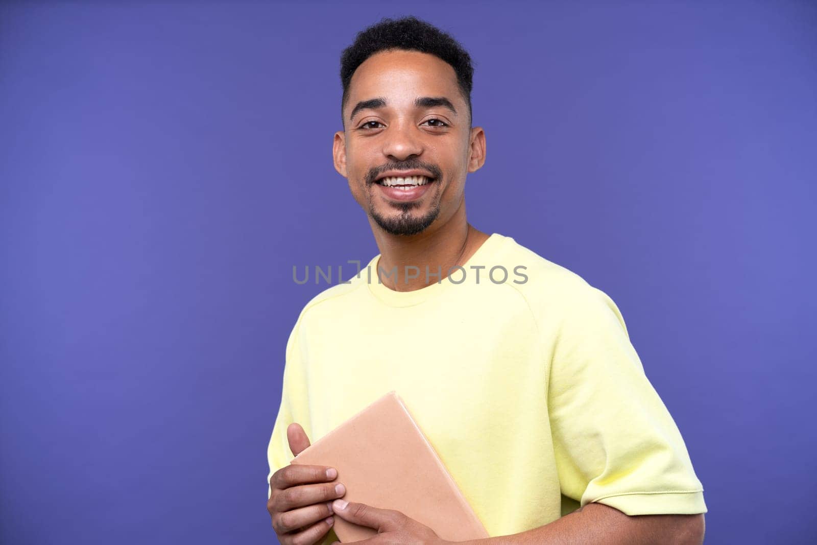 Emotional young black guy in casual raising fists up studio background, celebrating success, happy handsome african american millennial man sharing good emotions, copy space