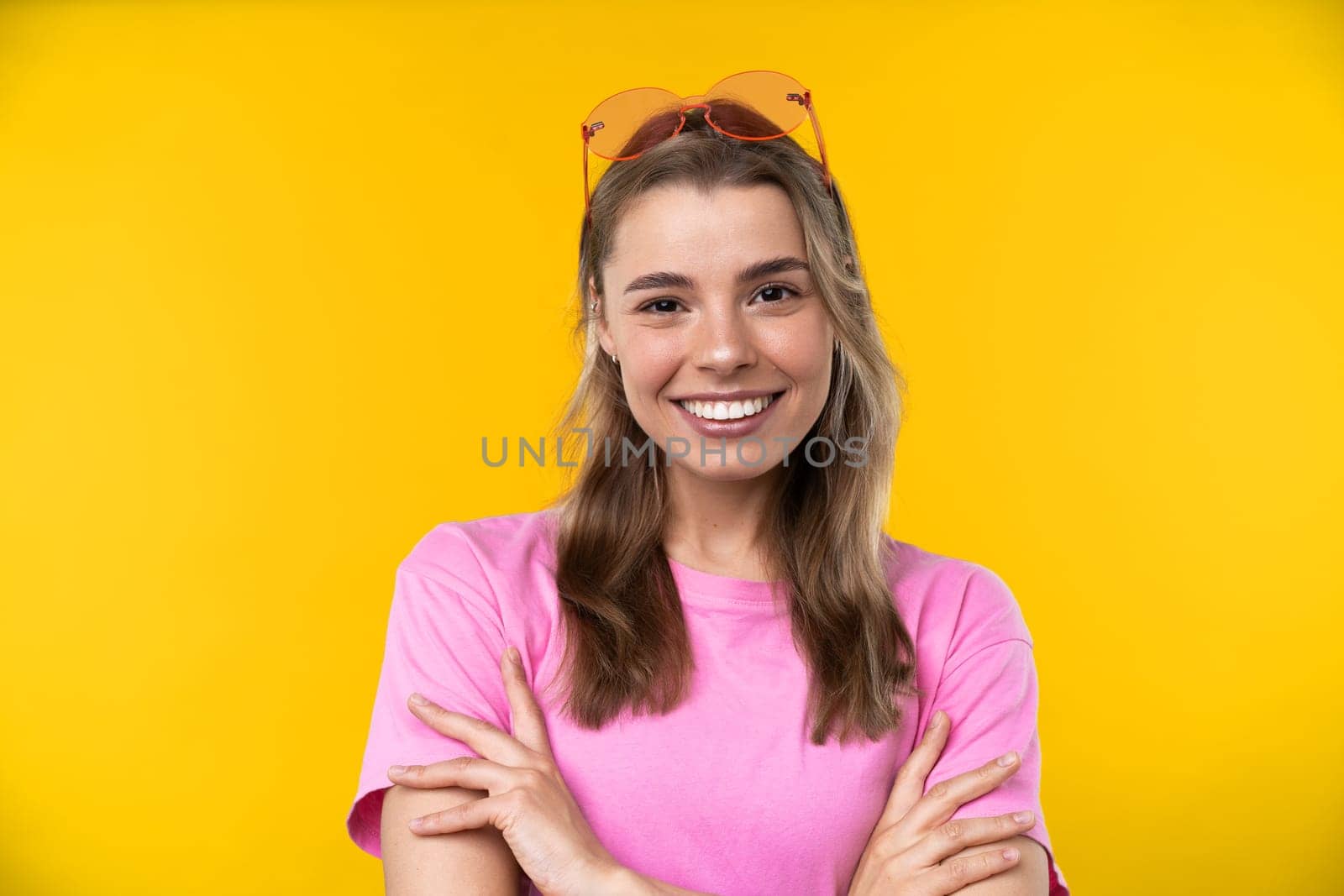 Happy emotions concept. Positive and beautiful young woman laughs poisitively looks aside with carefree face expression wears casual orange sweater isolated over yellow studio background.