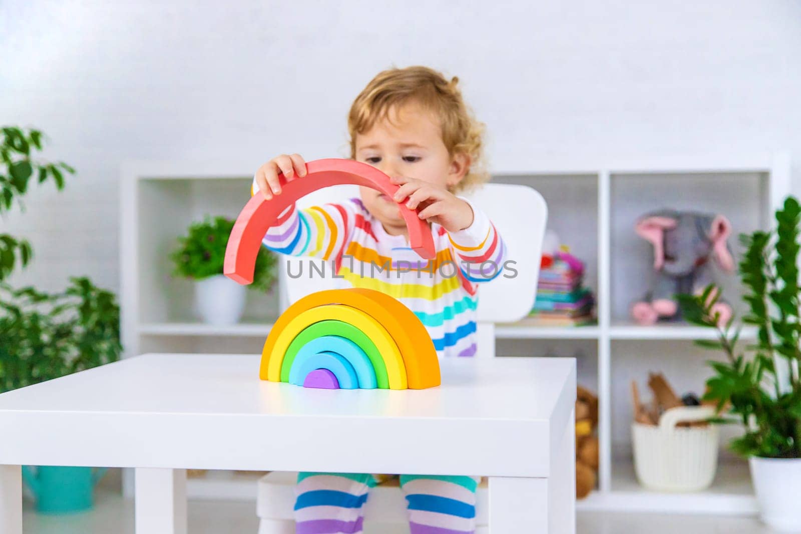 The child collects the constructor rainbow. Selective focus. Kid.