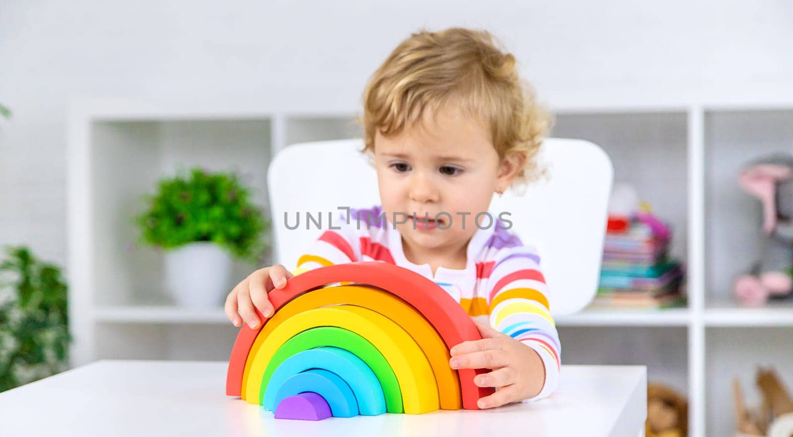 The child collects the constructor rainbow. Selective focus. Kid.