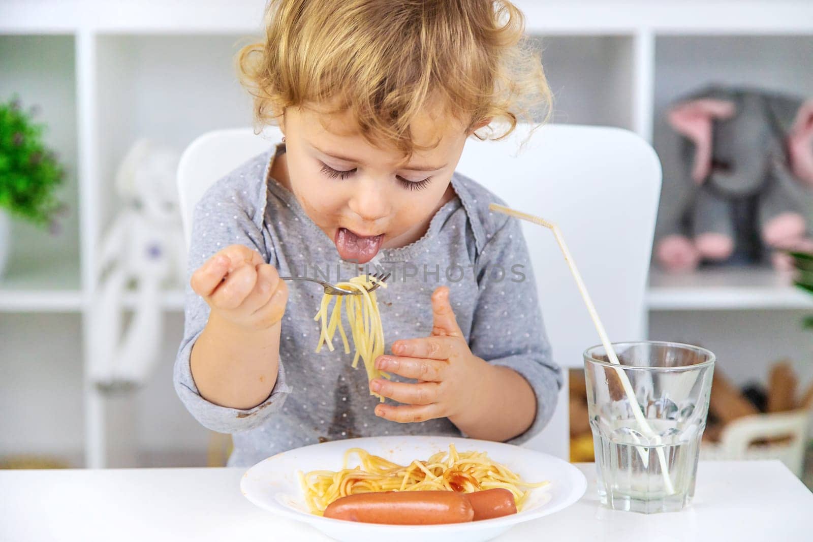 The child eats spaghetti lunch. Selective focus. Food.