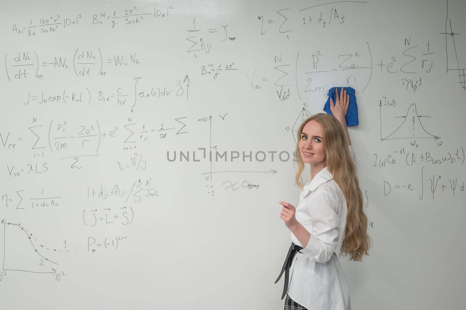 Caucasian woman erasing formulas from white board. by mrwed54