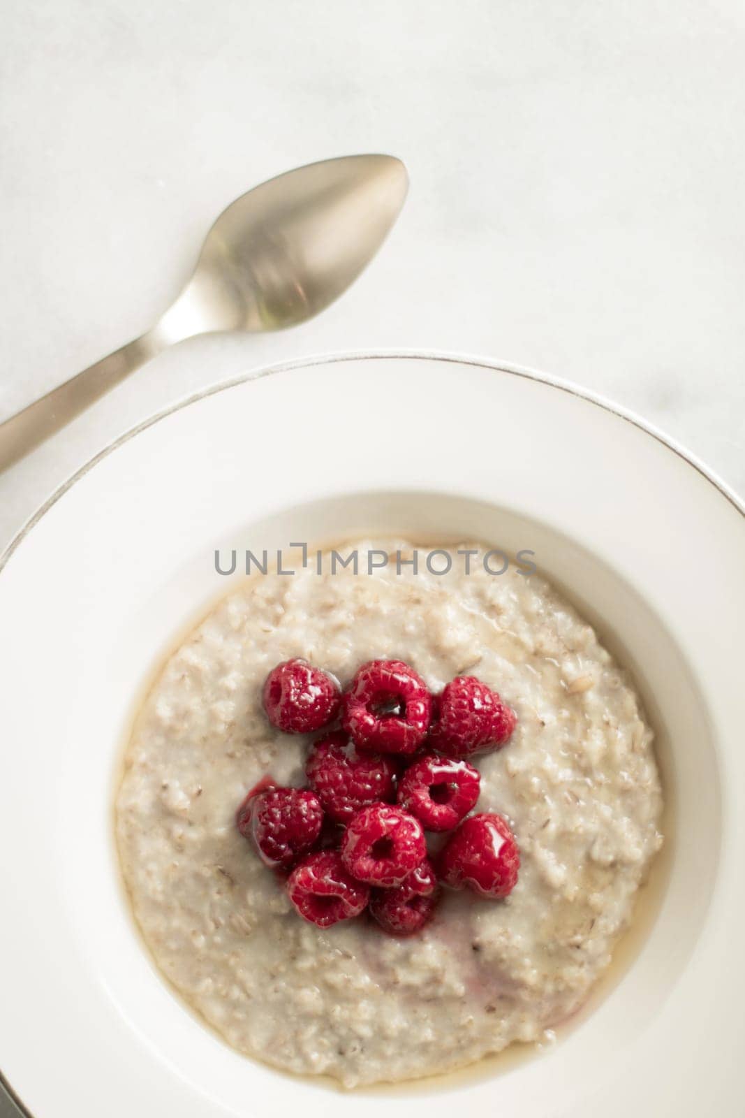 homemade rustic healthy breakfast styled concept - oatmeal with raspberries and honey, elegant visuals