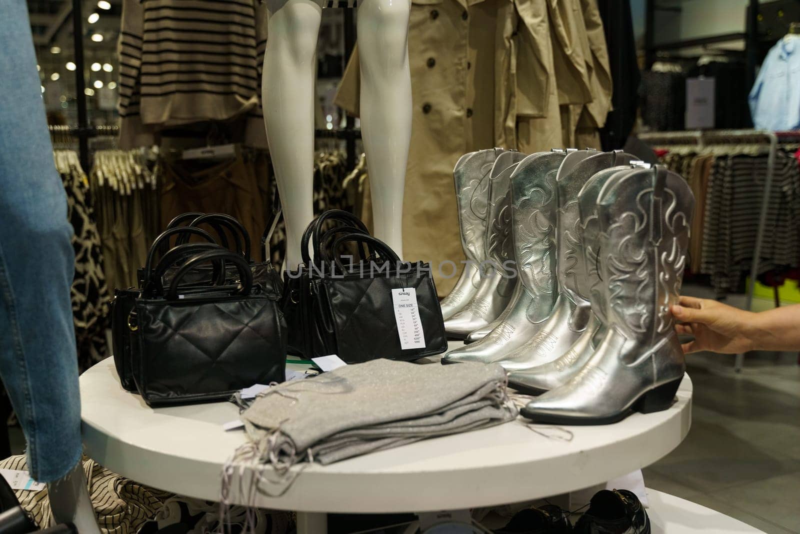 Klaipeda, Lithuania - August 10, 2023: A variety of boots and purses neatly arranged on a table, showcasing different styles and colors for sale or exhibition.