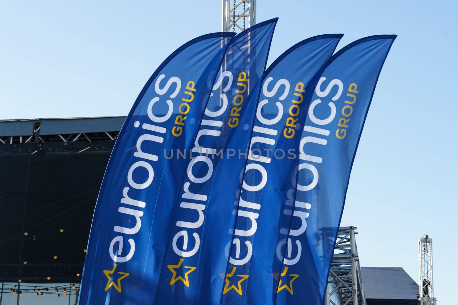 Klaipeda, Lithuania - August 11, 2023: Three blue Euronics Group feather flags stand tall with logos visible, swaying gently under a sunny sky.