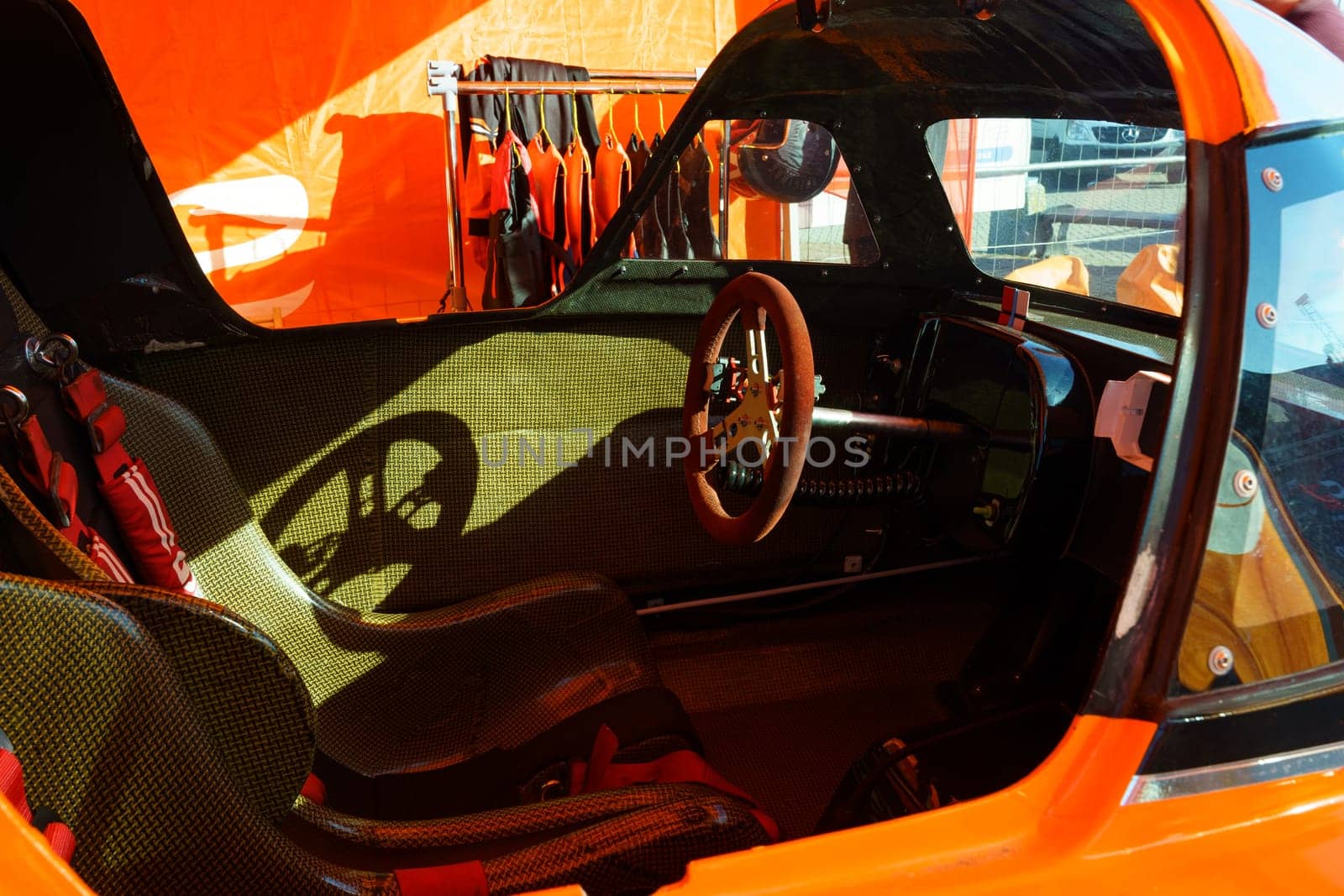 The interior of an orange car is shown, featuring a steering wheel and dashboard.