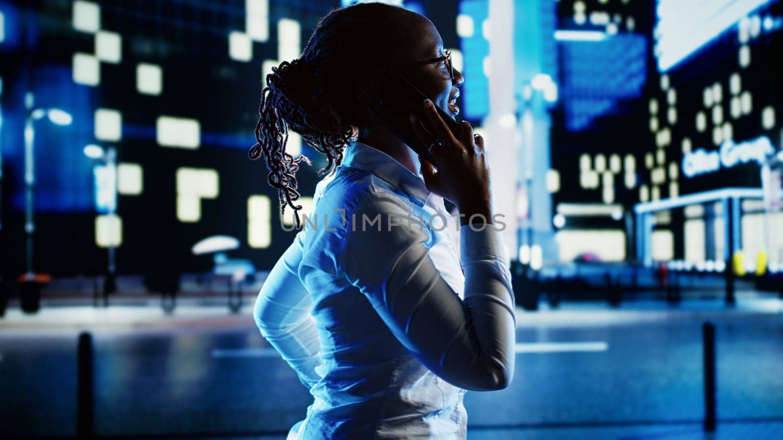 African american woman strolling around cityscape at night, enjoying conversation over the phone with husband. Businesswoman walking home from work having telephone call to make commute go faster