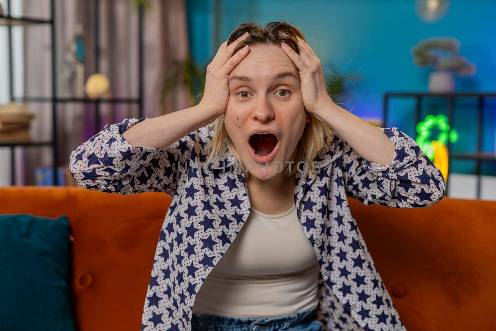 Oh my God, Wow. Excited amazed young woman surprised looking at camera with big eyes, shocked by sudden victory, good win news, celebrating success triumph. Portrait of happy Caucasian girl at home.