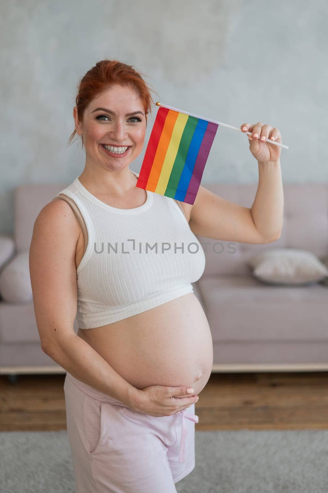 Happy pregnant woman holding a rainbow flag
