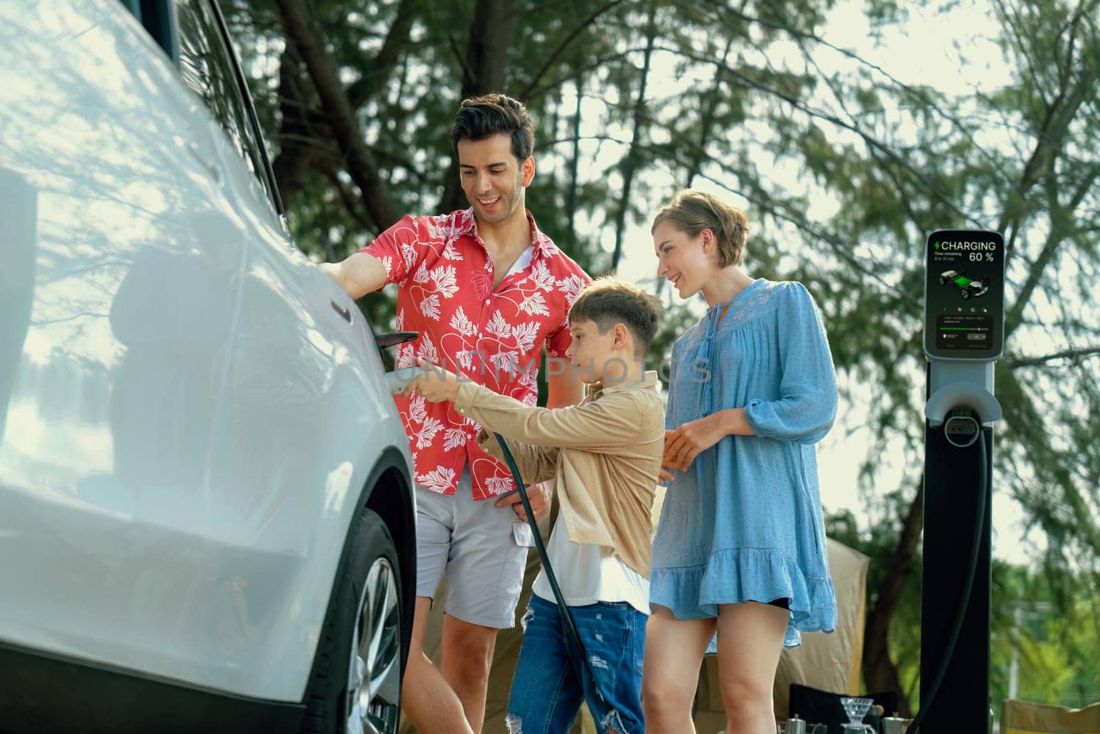 Lovely family recharge EV car with EV charging station in campsite. Perpetual by biancoblue