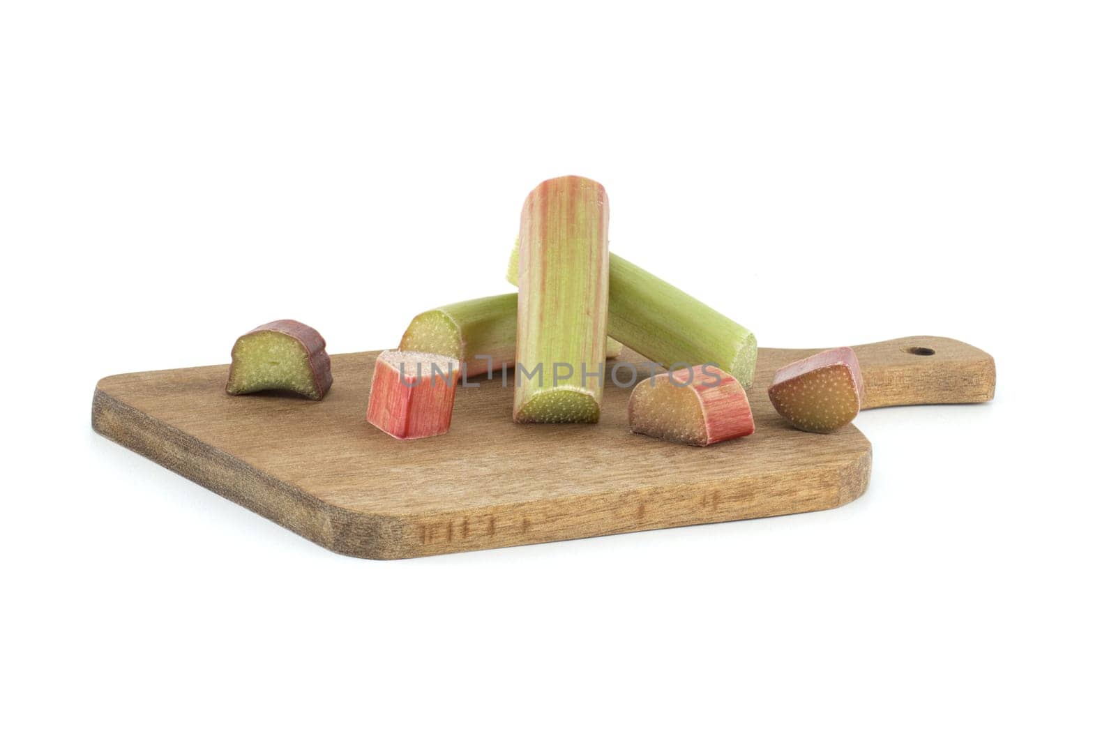Group of rhubarb pieces in various shapes and sizes arranged in a scattered formation on wooden cutting board isolated on white background