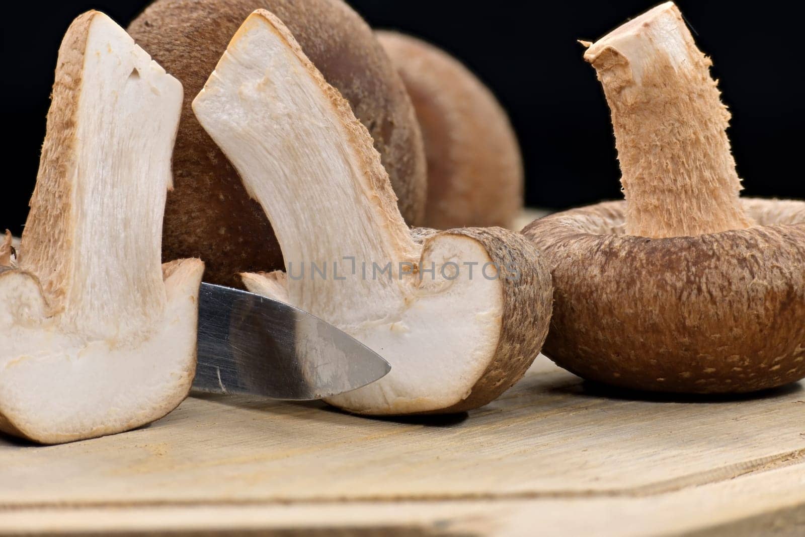 Fresh shiitake mushrooms on cutting board, one mushroom are cut, revealing their white interior, nutritional and medicinal, Lentinula edodes
