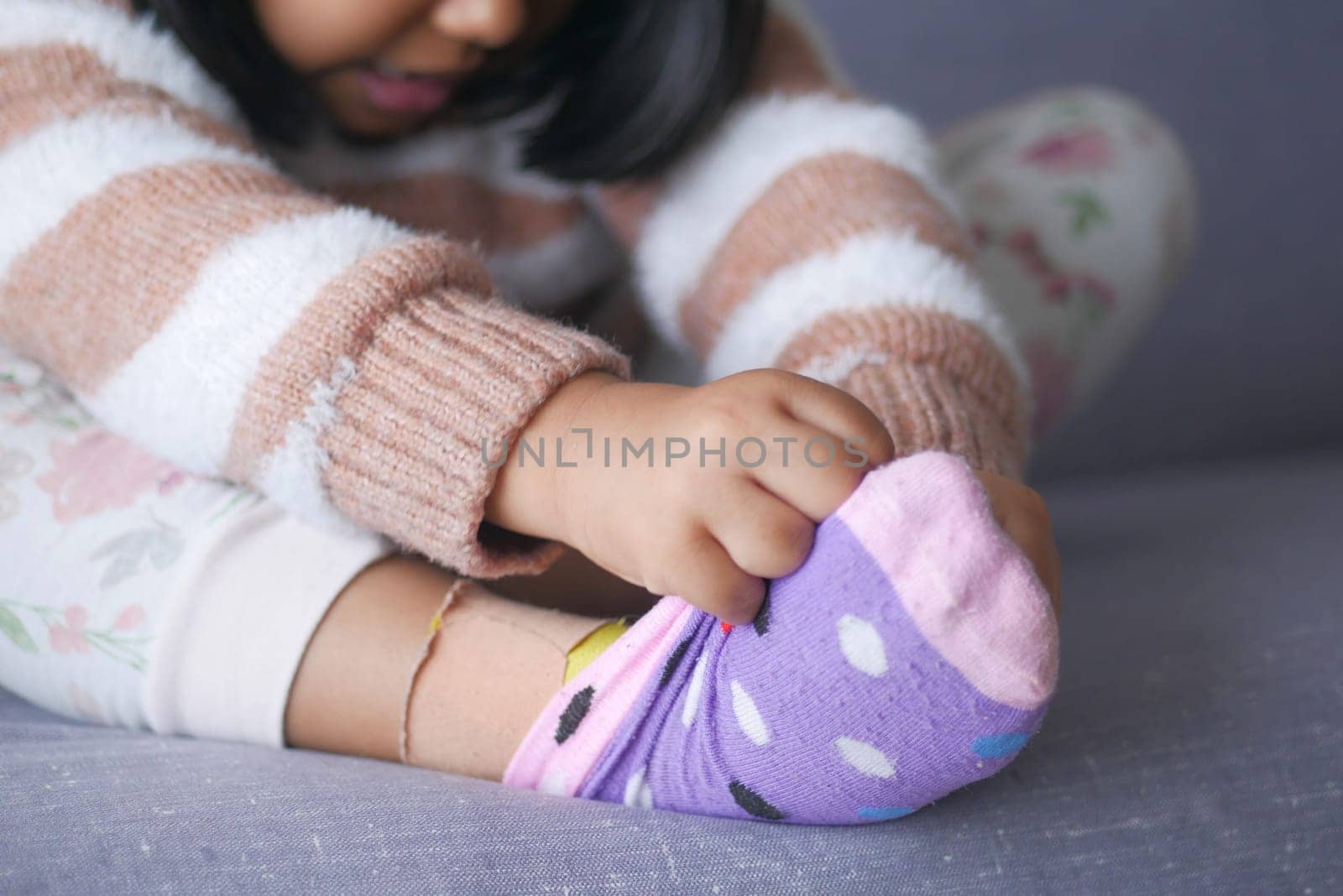 a little girl trying to take off her socks ,