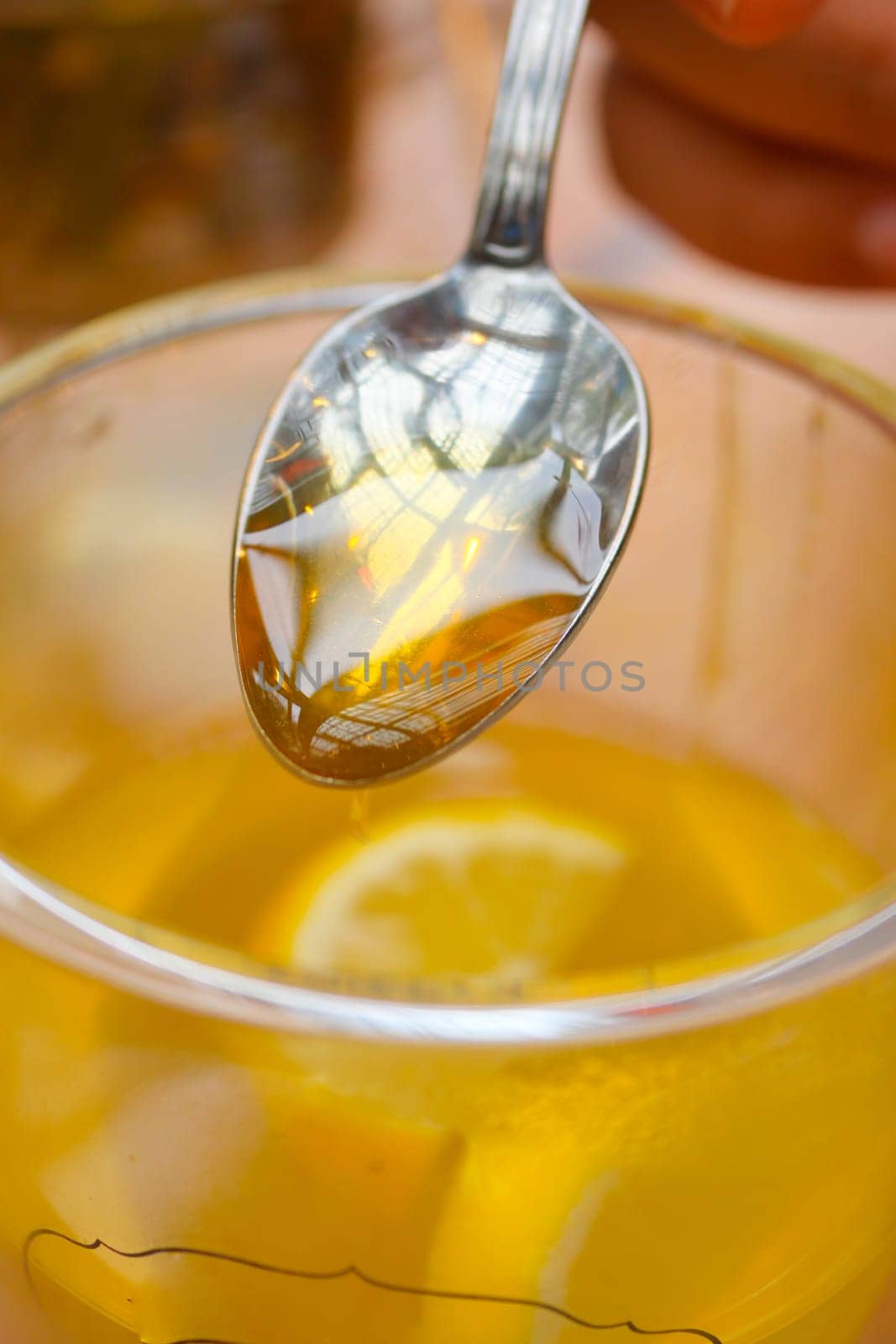 pouring honey in a cup of tea .