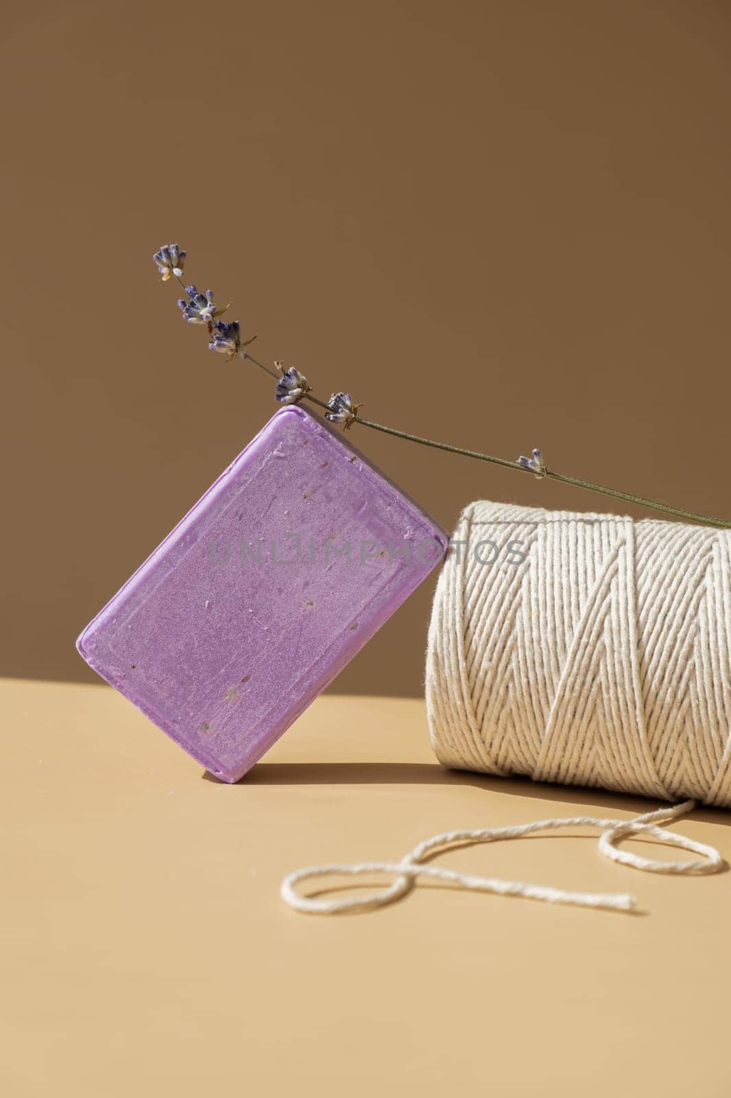 Lavender soap on beige background with spool of white cotton rope copy space for your text. Advertisement template mock up. Skincare homemade natural cosmetic concept. Organic dry lavender flower by anna_stasiia