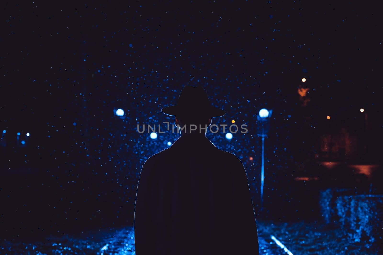 man detective agent in a hat and raincoat at night in a rainy city in the style of film noir