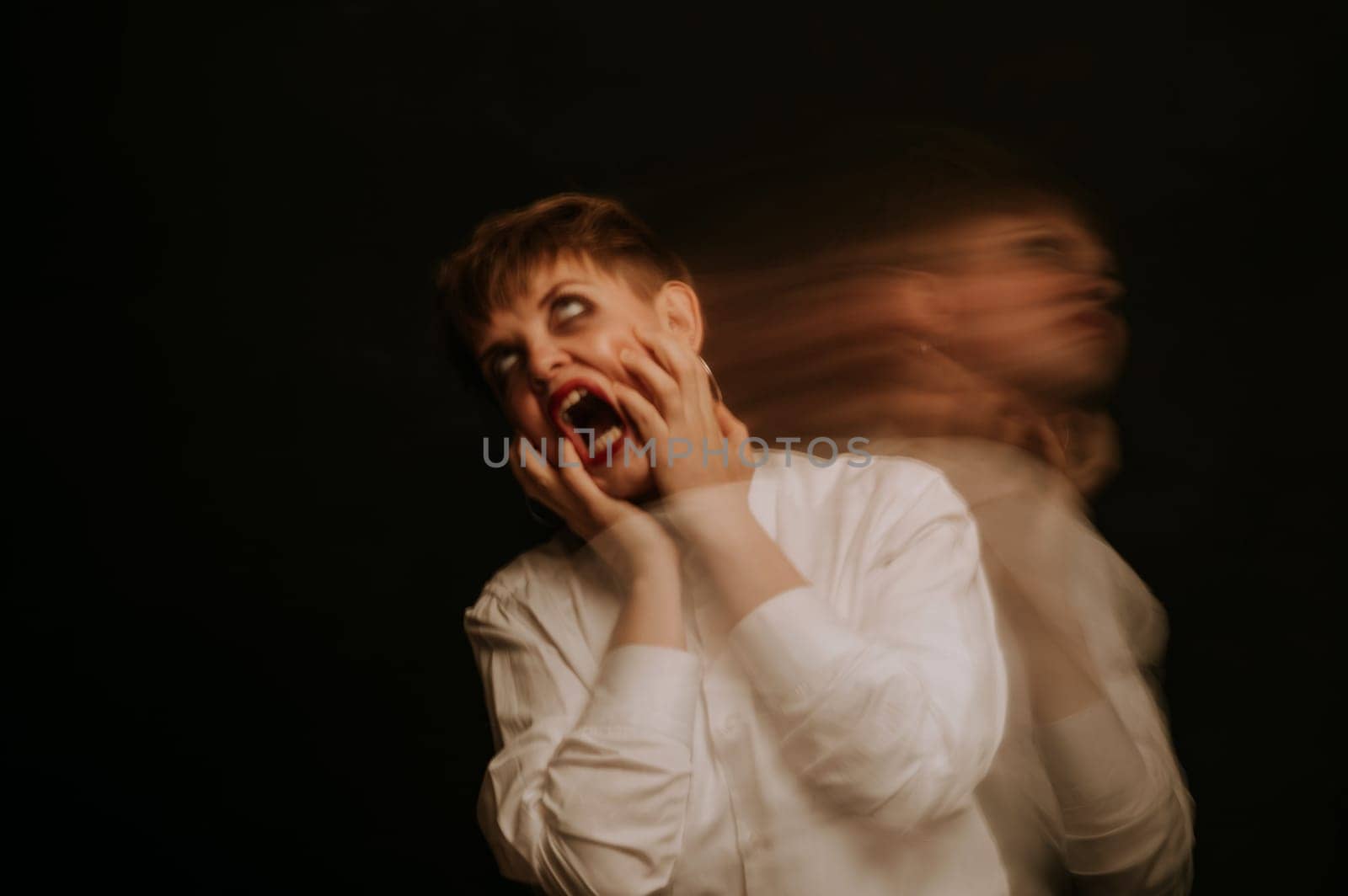 Blurry portrait of an emotional girl in a white shirt on dark background