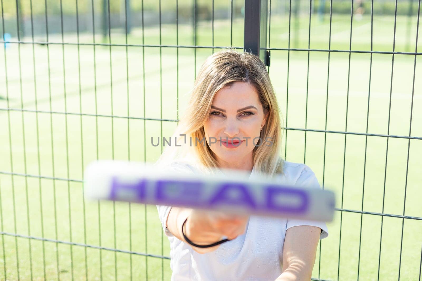 Ukraine Kyiv, May 03 2024. Portrait of smiling woman with padel tennis racket head at court. High quality photo
