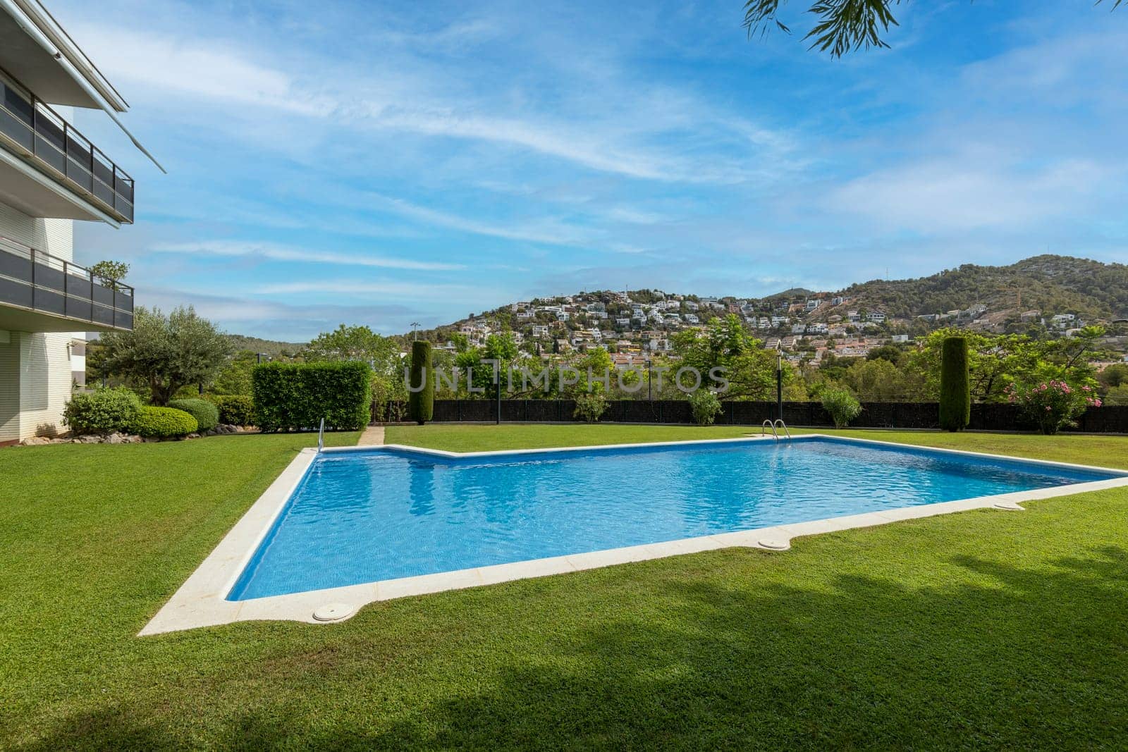 Crystal clear swimming pool bordered by a green lawn with a scenic mountain view by apavlin