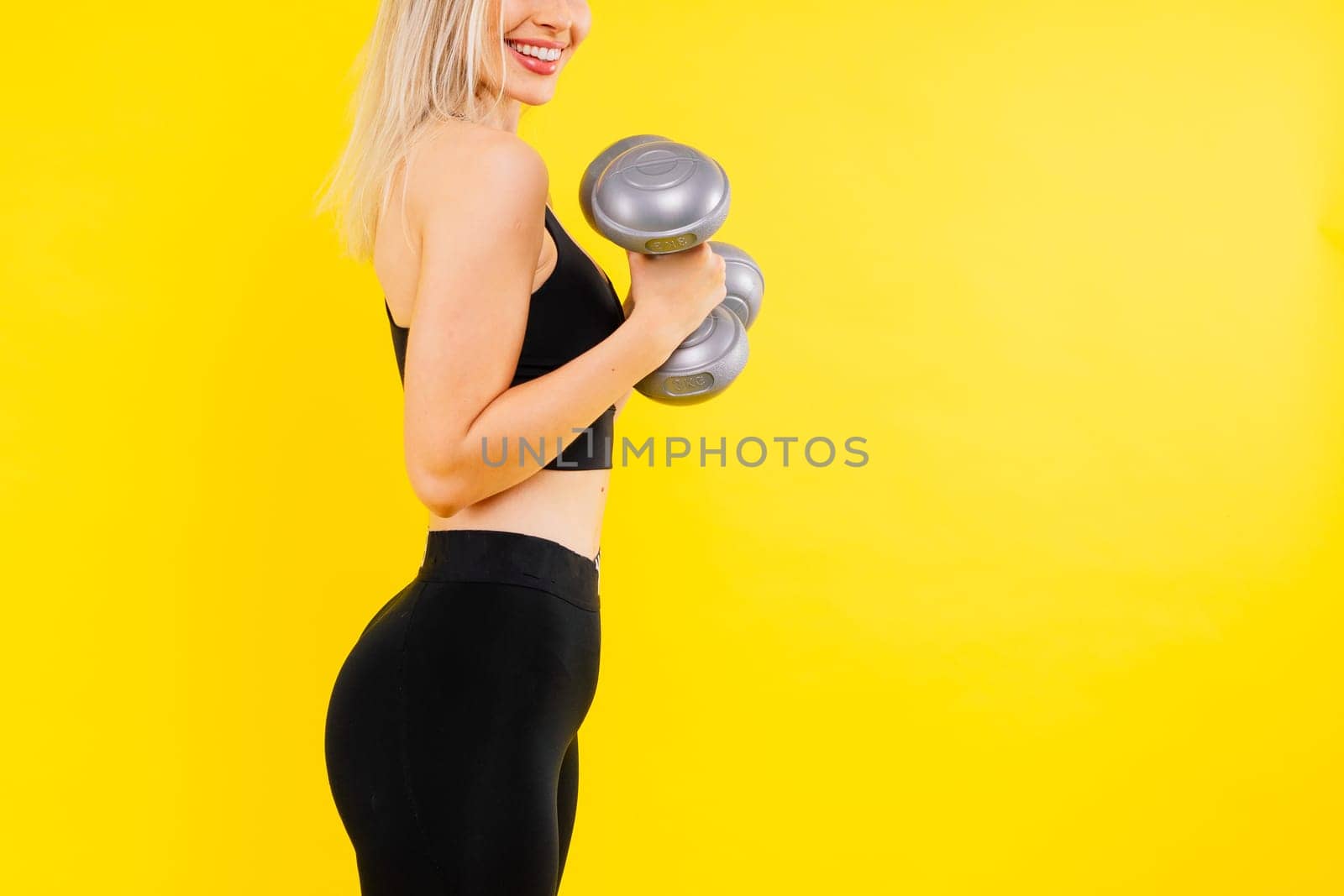 Strong woman working out with dumbbells, flexing her arm. Photo of sporty female in sportswear. by Zelenin