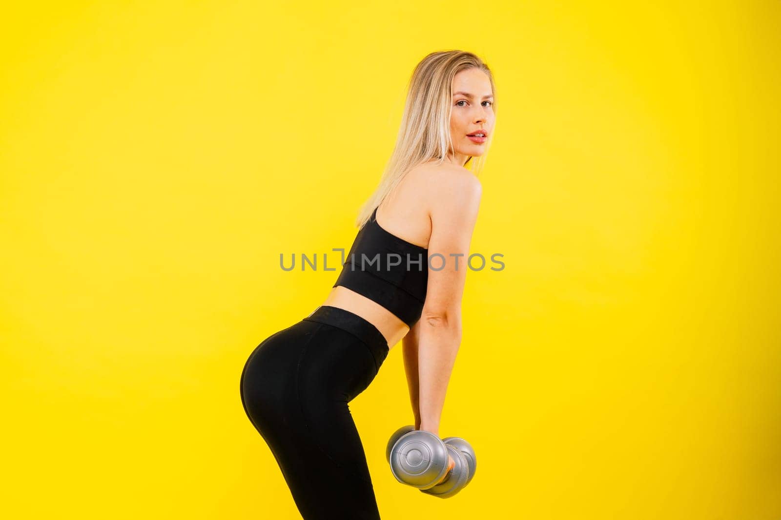 Strong woman working out with dumbbells, flexing her arm. Photo of sporty female in a sportswear.