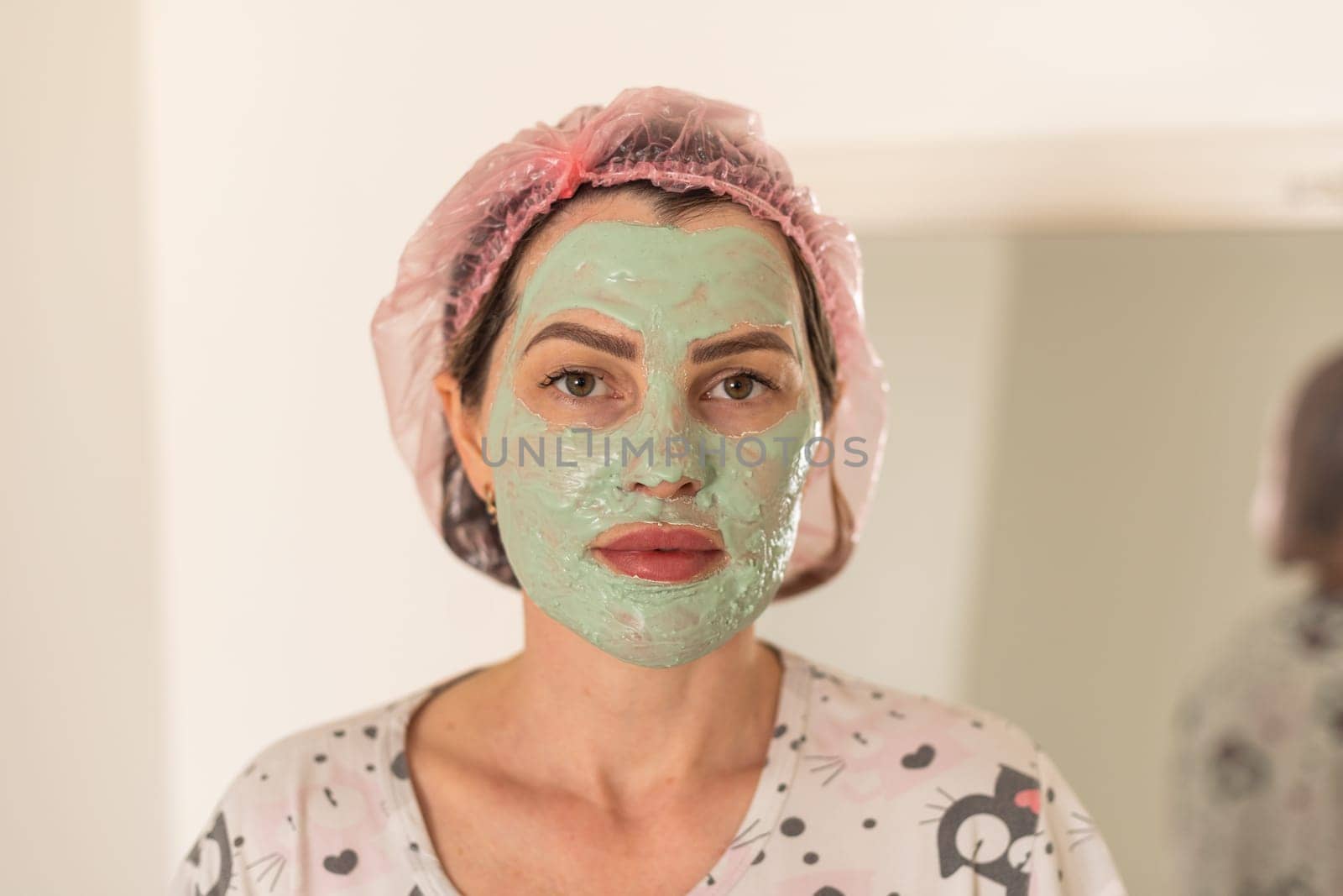 Self care: a woman applying clay mask to her face. High quality photo