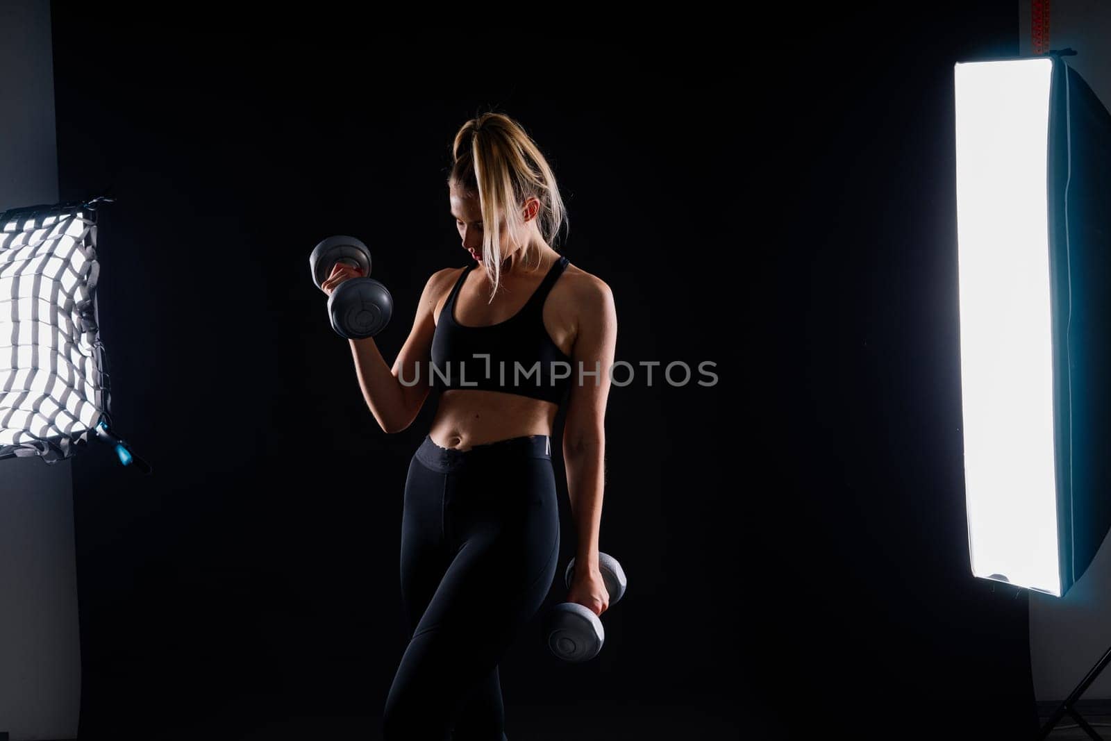 Strong woman working out with dumbbells, flexing her arm. Photo of sporty female in sportswear. by Zelenin